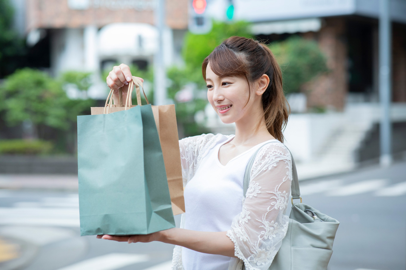 買い物をした後に紙袋を持ち上げてうれしそうに見ている20代のの女性