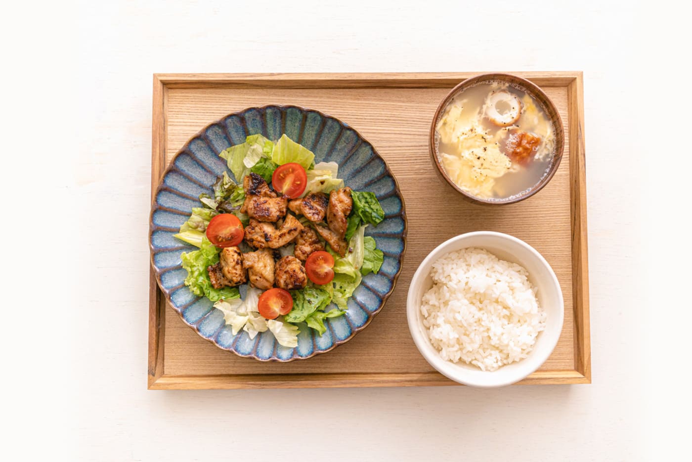 お盆に乗った鶏料理とご飯とみそ汁を上から撮影した写真