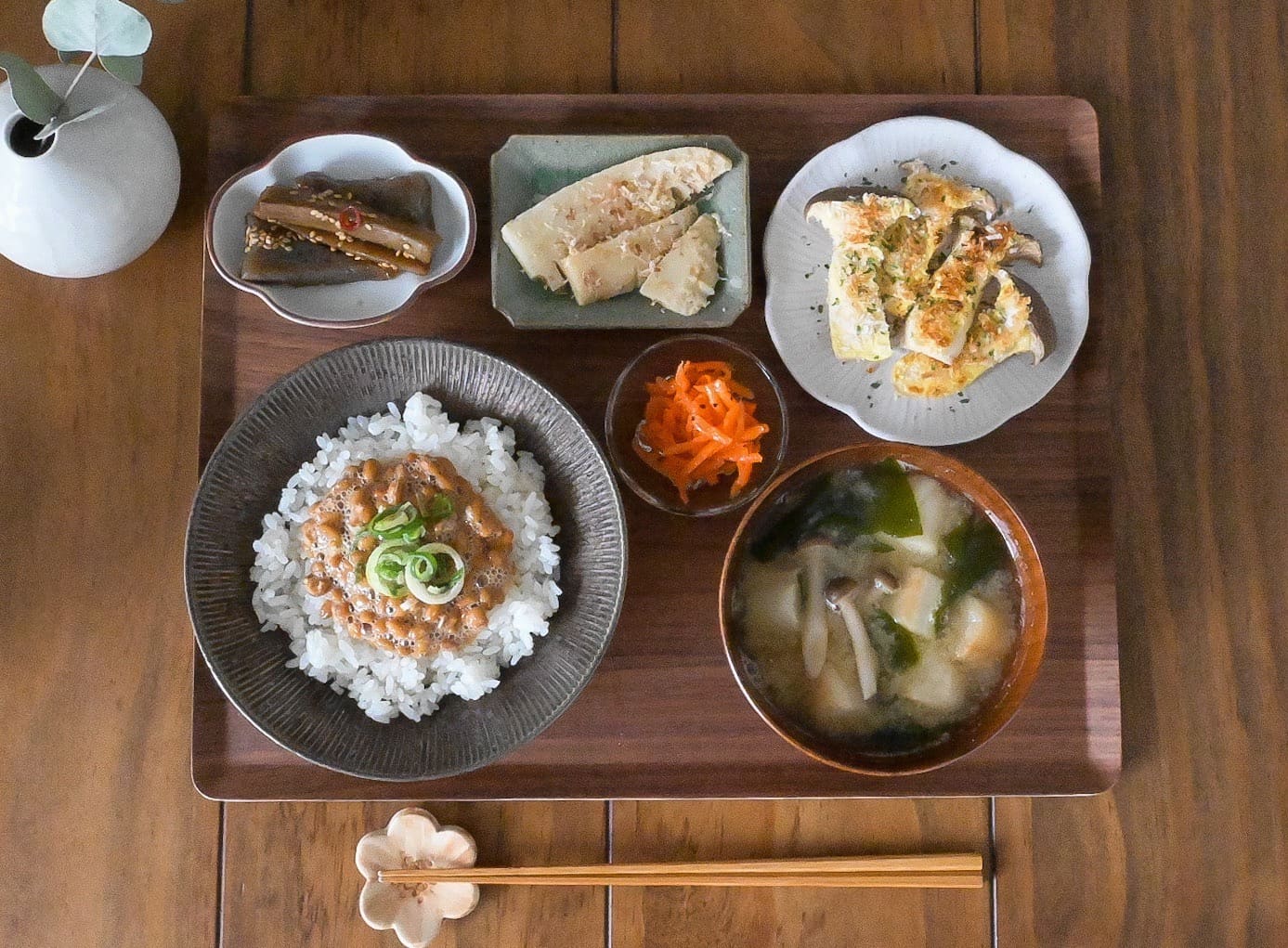 納豆ご飯とみそ汁とエリンギのソテーとタケノコの煮物とこんにゃくがお盆に乗った定食