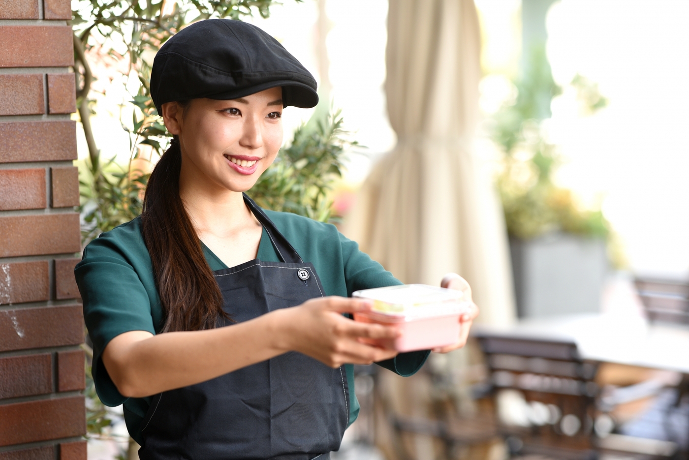 容器をさし出すハンチングをかぶった女性店員