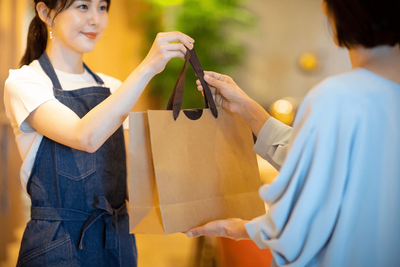 店員からお客様へ紙袋をお渡ししている様子。